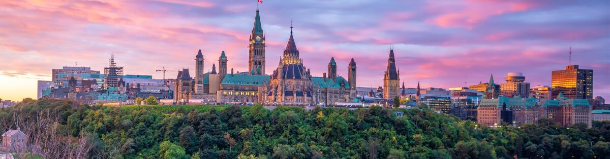 Aerial view of Ottawa/Parliament Hill during sunset with purples, pinks & oranges throughout the skyline.
